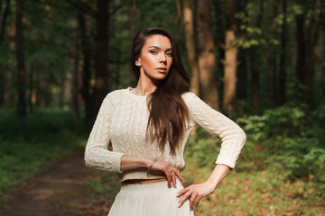 Obraz premium Beautiful natural fresh young woman in a fashion knitted sweater on a green natural background in the forest