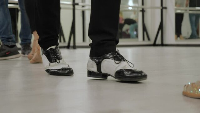 joyful dance practice in the hall on the parquet. reflection of dancing couples in the mirror. teachers show salsa and ballroom dancing movements.female legs in high heel shoes. legs of a man in shoes