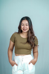 Portrait of a confident Asian woman smiling, standing looking at the camera isolated on a blue background