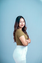 Portrait of a confident Asian woman smiling, standing looking at the camera isolated on a blue background