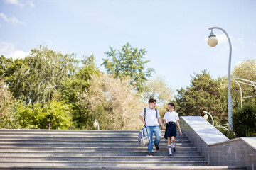 boy and a girl, two teenagers, friends, go to school, go down the stairs, laugh merrily. Back to School. Copy space