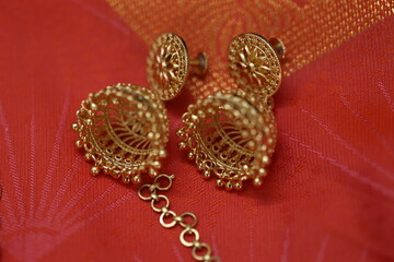 a pair of gold earring on a silk saree