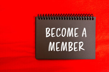 Become a member message written on black notebook page with red background. Conceptual become a...