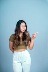 An excited young woman presents and points up the copy space, isolated on a white background