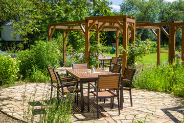 Obraz premium Wooden terrace. chair, table at the background of beautiful flowering garden