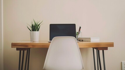 A minimalist workspace with a clean, wooden desk, a single laptop, and a small potted plant