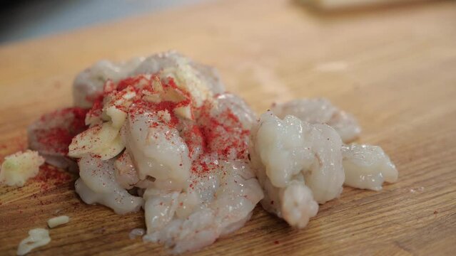 raw prawns meat marinating with herbs and spices. chef cooking. restaurant kitchen. closeup seafood. shrimp on a wooden board and sprinkles spices on the seafood