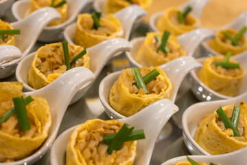 Pad Thai wrapped in egg served in a spoon in the event, close up