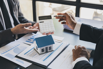 House model with agent and customer discussing calculate for price contract to buy, get insurance or loan real estate or property.