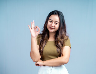 Fototapeta premium Young beautiful woman smiling joyfully and looking happy, feeling carefree and positive isolated by blue background