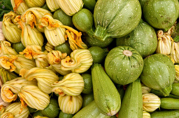 
Detailed Description:
A close-up view of fresh green zucchinis and zucchini blossoms, showcasing their natural texture and vibrant colors, emphasizing freshness and organic produce.