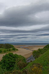 The view over the River Lunan River running into the North Sea at Lunan Bay on a dark and rainy day in June at an exceptionally Low Tide.