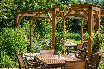Obraz premium Wooden terrace. chair, table at the background of beautiful flowering garden