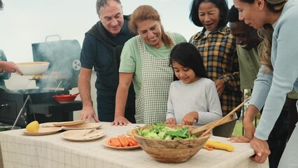 Multi generational people having fun doing barbecue at house rooftop - Happy multiracial friends cooking together - Summer gatherings and food concept