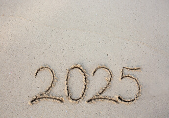 New Year 2025 handwritten in the white sand surface.