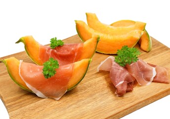 Cavaillon with Parma ham finished with parsley, served on a wooden cutting board. Tasty and festive appetizer. Selective focus.