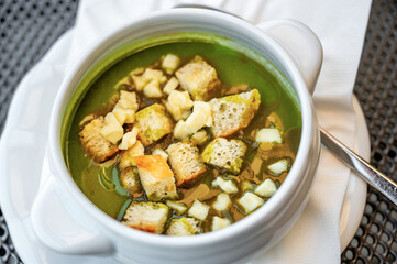 Bowl with spinach soup with fried bread and cheese.