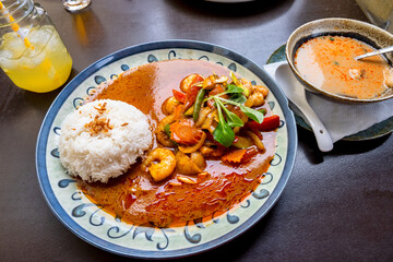 Red curry with shrimps and vegetable, soup and drink on table.