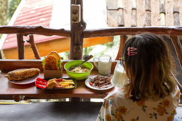 rear view of beautiful woman in glasses with slightly curly hair taking photos of some delicious and hot food using smart phone