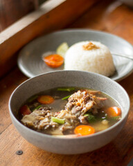 Sop Buntut or oxtail soup on a wooden table. traditional Indonesian culinary delights