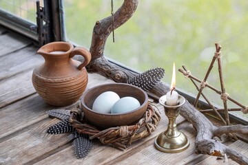 Home pagan spring altar with willow wreath, clay jug with milk, eggs, burning candle and birds...