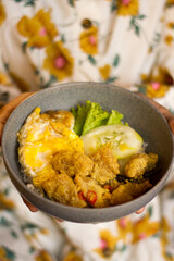 hands carrying crispy salted egg dori, in a wooden-themed cafe