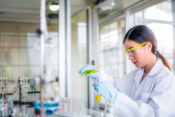 Attractive young Asian scientist woman lab technician assistant analyzing sample in test tube at...