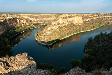 Obraz premium View from a rocky shoreline on a cliff of the Duraton river running through a beautiful sickle at sunrise, Duraton River Sickles Natural Park at sunrise, Sepulveda, Segovia, Spain