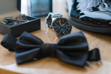 Elements of a businessman's clothing on a table. Shoes, perfume, watch, cufflink and groom's...