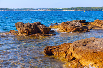 Sea is calm and the rocks are scattered around the shore. The water is clear and the rocks are brown. Rocks on the coast of the Adriatic Sea in Croatia