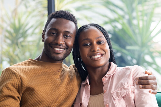 Young African American couple sits closely, smiling and enjoying their time at home