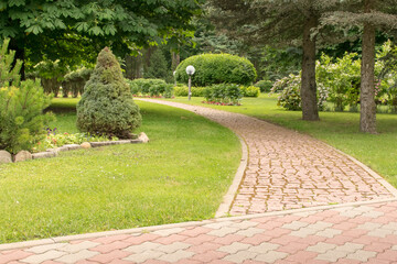 a beautiful and well-kept park with paths of fir trees and flowers