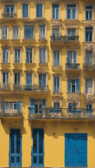 Fototapeta premium Yellow facade and windows with blue shutters on old building