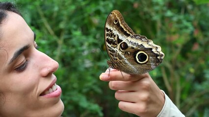 young Latina holding an Owl Butterfly (Caligo memnon) at the butterfly garden in Mindo, Ecuador