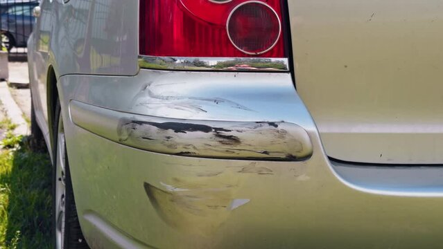 Closeup of a damaged car bumper in daylight, with visible scratches and dents. Repair and maintenance may be required for this vehicle