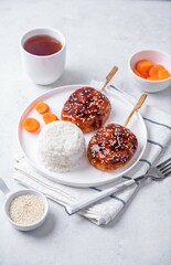 Tsukune, Japanese Chicken Meatball in teriyaki sauce with sesame seeds sprinkles with rice and vegetables in a plate