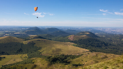 parapente survolant la chaîne des Puys, également appelée Monts Dôme, un groupe d'environ 80 volcans situé sur le plateau des Dômes au nord du Massif Central, en France.