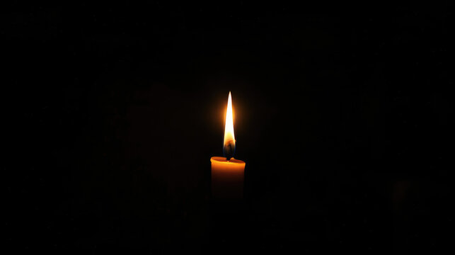 A single candle with a bright flame stands alone in the darkness, casting a warm light.