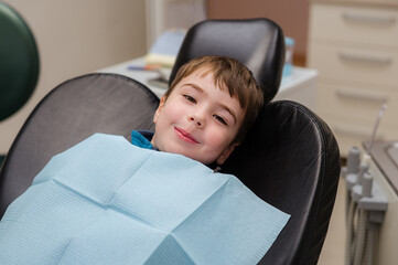 A cute little boy in a dental chair treats his teeth, smiling and happy © Ольга Апанасенко