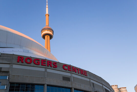 Rogers centre and CN tower at sunset time. Baseball stadium and new modern skyscrapers. Architecture of downtown Toronto, Ontario, Canada - 06.02.2024