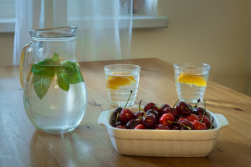 Sweet cherries, mint water and orange drink on the kitchen table