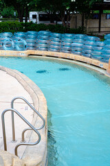 Swimming pool handrails along lazy river with depth marker and full stack of clear floats at upscale hotel resort in Grapevine, Texas, transparent bathing swimming rings near entrance metal fence