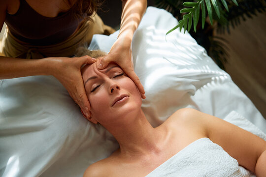 Mature woman having face massage by masseuse in a spa