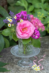 Blumenstrauß mit pink Rose, Hortensienblüten, Wicken, Lavendel und Mutterkraut in Glasvase im Garten