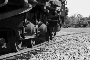 Ferrocarril antiguo saliendo de una estación, foto en escala de grises.
