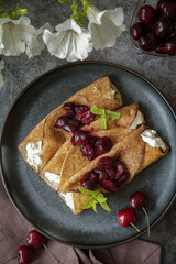 Crepes with ricotta cheese served on the plate with blueberries, strawberries and cherries