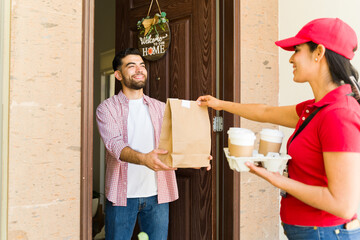 Cheerful female delivery driver delivers a bag of food and coffee to a customer's doorstep