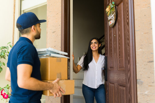 Happy woman receiving a home delivery from a delivery man holding cardboard boxes at the entrance of a house