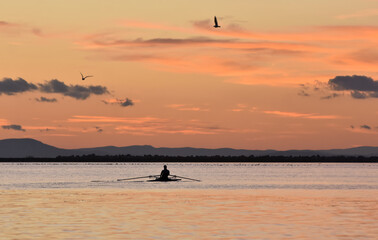 Silhouette of a person  rowing on a boat at sunset