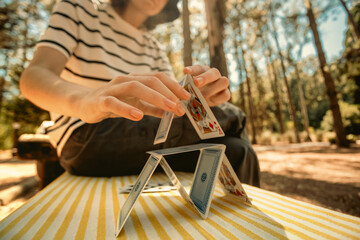 Smiling teenager girl playing card game with family. Creative outdoors leisure and education of kid. Family activity at the park.
